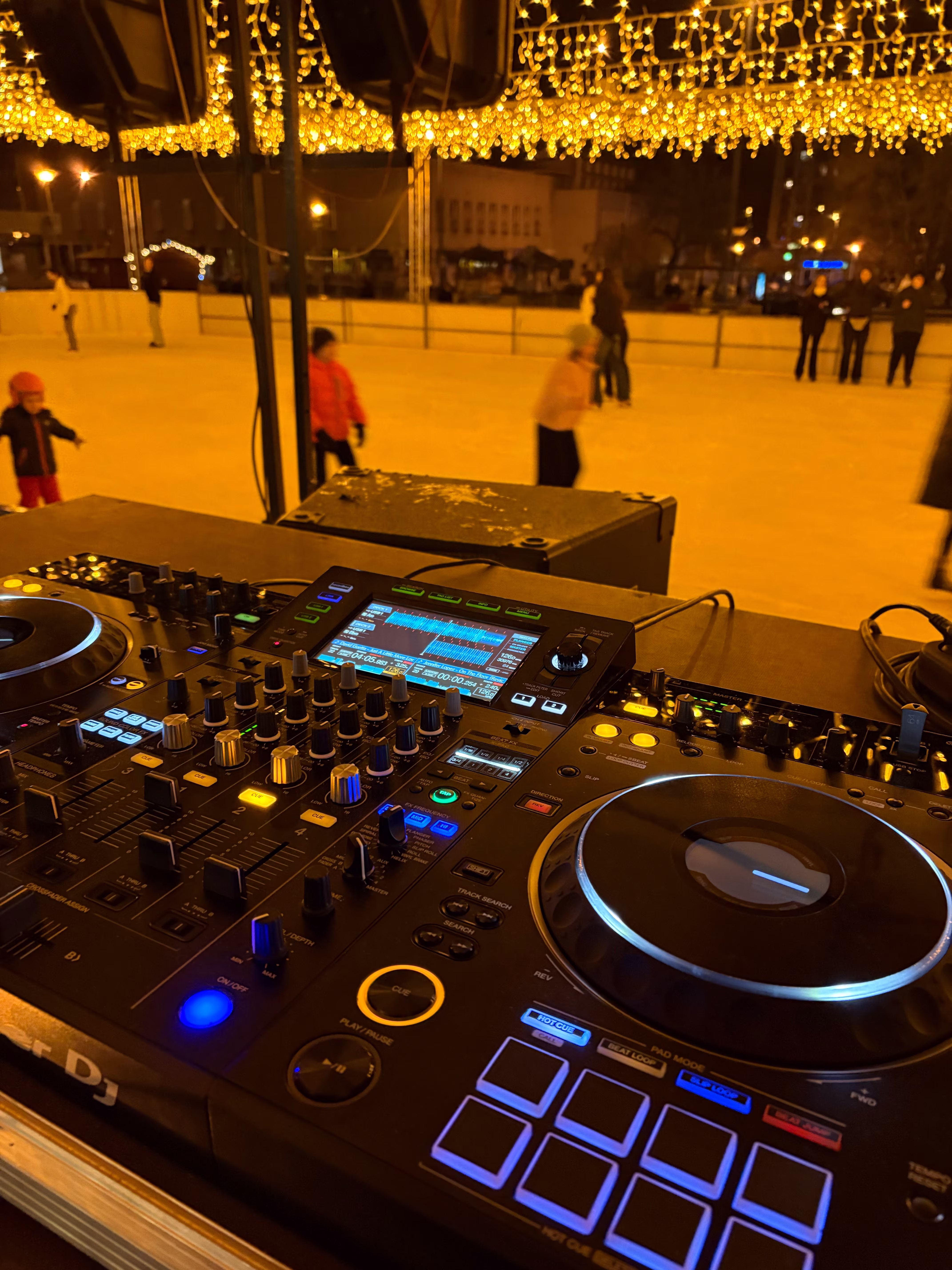 Szélesvásznú kép a JégDisco jégpályájáról és DJ pultról.